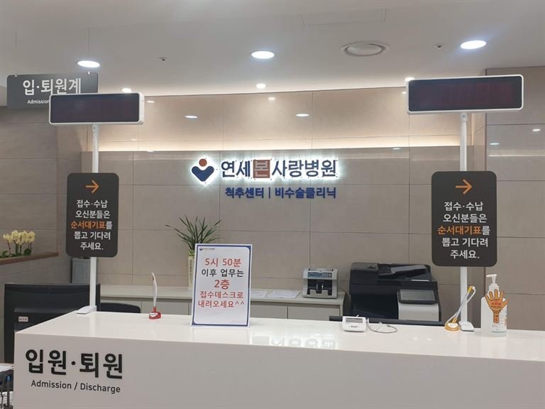 병원 접수 데스크 뒤 백라이트 로고 사인